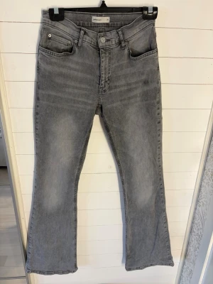 Grå bootcut jeans från Gina Tricot - Säljer ett par gråa lågmidjade bootcut jeans från Gina Tricot. Dom är i storlek 38, och lite tajtare vid midjan. Men ändå i mycket stretchigt material.              Dom är bara använda ett fåtal gånger, så jätte fint skick men lite slitna längst ner, bak på byxorna. Hör gärna av dig om du har några funderingar!
