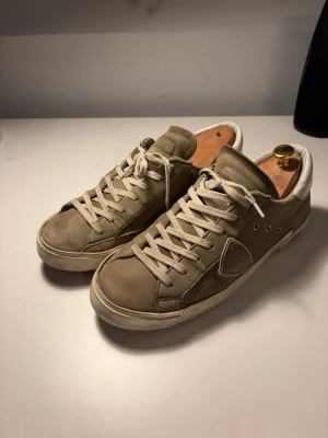 Philippe Model grå sneakers - Snygga sneakers från Philippe Model i grå mocka med vita detaljer och vita skosnören. Klassisk modell. Välanvända skor, därav priset. Inkluderad original box och nya gröna tillhörande snören.