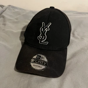 Svart YSL x New Era keps - Snygg svart keps från YSL och New Era. Säljer då den inte kommer till användning. Mitt Pris. 199, Nypris 2300. Hör av er i dm vid intresse/ mer bilder.