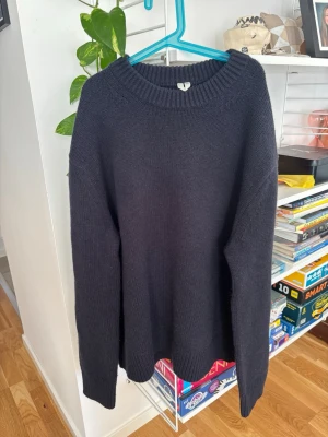 Mörkblå stickad tröja unisex - En enkel och stilren mörkblå stickad tröja med rund halsringning och ribbade muddar. Tröjan har en avslappnad passform och är perfekt för lager på lager. Passar både killar och tjejer. Den är i toppskick då jag aldrig har använt den pga att den e lite för liten för mig!