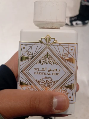 Lattafa Bade'e Al Oud Honor & Glory 100ml  - Lattafa Bade'e Al Oud Honor & Glory är en parfym i en vit, fyrkantig flaska med guld- och silverdetaljer i geometriskt mönster. Flaskan har en stilren design och kommer i en matchande förpackning med genomskinligt fönster. Perfekt för dig som gillar exklusiva dofter.