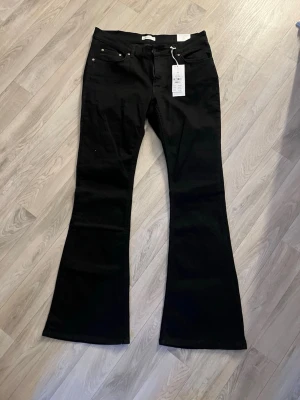 Svarta bootcut jeans från Gina tricot  - Snygga svarta bootcut jeans från Gina tricot med låg midja och klassisk femficksdesign. Jeansen har utsvängda ben och är tillverkade i stretchigt material för en bekväm passform. Perfekta för dig som gillar en trendig och avslappnad stil. Katt finns i hemmet