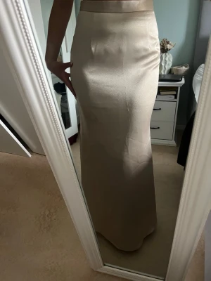 Satin kjol - Superfin satinkjol. Hög midja och slutar vid fötterna (jag är 167cm). Har en dold kedja där bak. Köpt i butik med en tillhörande korsett, se sista bild. Paketpris om man vill köpa hela settet. Använd endast en gång. I storlek xs/s