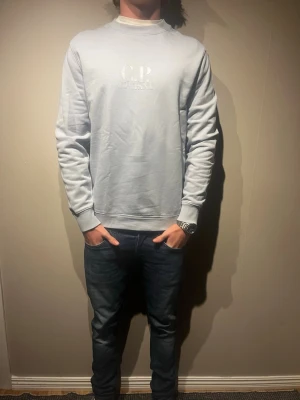 Ljusblå sweatshirt från C.P. Company - Sweatshirt ifrån c.p company i storlek S köpt i c.p company butiken i London. Färgen är ljusblå/babyblå. Modellen är 177cm och väger 65kg. Tröjan är äkta. Nypris:- 2249kr skriv för mer info✨✨ 