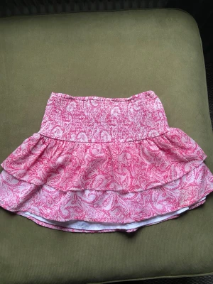 Rosa mönstrad kortkjol från Gina Tricot - Supersöt kortkjol från Gina Tricot i rosa och vitt med paisleyinspirerat mönster. Kjolen har smock i midjan och volang för en extra flowy känsla. Perfekt för dig som gillar färg och mönster!❤️
