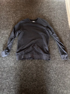 Mörkblå sweatshirt från Jack & Jones - En stilren svart sweatshirt från Jack & Jones med rund halsringning och ribbade muddar. Perfekt för en avslappnad look och enkel att matcha med jeans eller joggers.