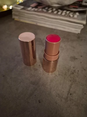 Krämrouge i stickform, rosa nyans - Snygg krämrouge i stickform med metalliskt roséguldfärgat hölje. Färgen är en fräsch rosa ton som ger kinderna ett naturligt glow. Enkel att applicera direkt på huden och perfekt att ha med i väskan. Märket är inte synligt på förpackningen. Ny.