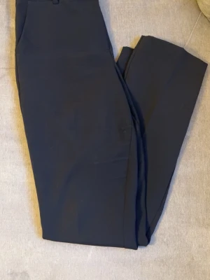 Svarta kostymbyxor från bik bok - Stilrena svarta kostymbyxor från bikbok med utsvängda ben och klassisk passform. Byxorna har fickor i sidorna, dragkedja och knapp. Perfekta för en clean och snygg look. Har egentligen storlek 36 men storlek 38 passar mig bättre då mina höfter är lite bredare.