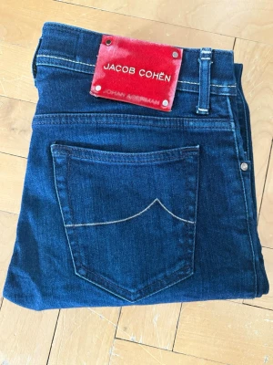 Jacob Cohën Jeans W31 - Hej! Säljer ett par Jacob Cohën 622 i storlek W31-L32 (105 cm långa). Slim passform.                                                Mörkblå jeans i mycket bra skick (nästan som nya).   Tillverkade i Italien.                                                   Skick: 9/10  Nypris: ca 5200kr                                   Hör av dig vid frågor eller intresse!
