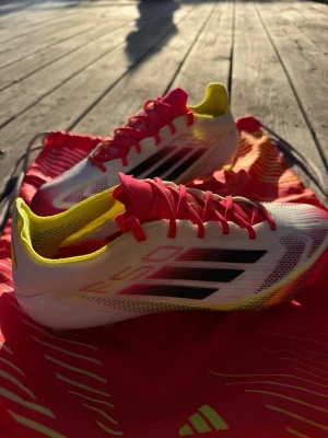 Adidas F50 vita/röda/gula fotbollsskor - Säljer mina adidas F50 Elite AG fotbollsskor i röd/vit/gul i storlek 36⚽🔥  Otroligt lätta och snabba skor från adidas populära F50-serie – perfekta för spelare som vill ha fart, grepp och bra bollkontroll på konstgräs. Vi blev sponsrade av laget med dessa skor, men eftersom jag personligen föredrar att spela i Nike väljer jag att sälja dem vidare istället ⭐️