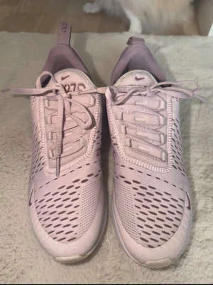 Nike Air Max 270 ljuslila sneakers - Nike Air Max 270 sneakers i ljuslila med mesh-ovandel och synlig Air Max-dämpning i hälen. Snygga detaljer med mörklila logga och 270-tryck på sidan. Skorna har klassisk snörning och sportig design som passar perfekt till streetwear.
