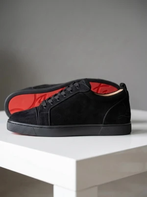 Svarta Louboutin sneakers i mocka - Snygga svarta sneakers från Christian Louboutin i mocka med klassisk röd sula. Skorna har lågt skaft, svarta skosnören och diskret branding på hälen. Perfekta för dig som gillar stilrena och exklusiva sneakers med en lyxig touch. Sprillans nya!!! Skickar inom 1-5 timmar låda också 