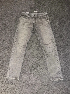Jack & Jones - Snygga grå slim fit jeans från Weekday med klassisk femficksdesign och dragkedjegylf. Jeansen har en tvättad look och raka ben, perfekta för en avslappnad streetstyle. Materialet är bomullsdenim med en skön känsla.