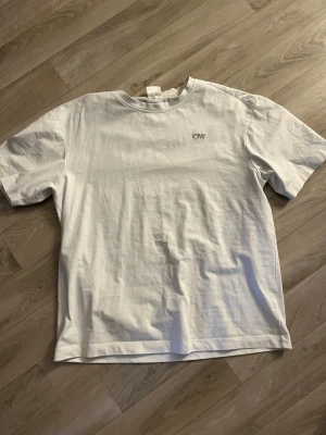 Vit t-shirt från ICIW  - Klassisk vit t-shirt från ICIW med diskret logga på bröstet. T-shirten har rund halsringning och korta ärmar. Katt finns i hemmet!