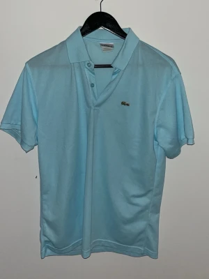 Lacoste pike ljusblå - Snygg ljusblå piké från Lacoste som är ny och använd fåtal gånger. Pris kan diskuteras 