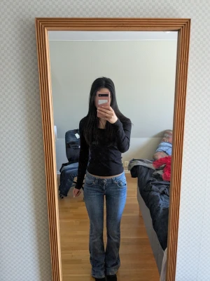 Blå bootcut jeans med låg midja - Säljer ett par klassiska blå bootcut jeans med låg midja och fem fickor. Jeansen har en lätt tvättad look och sitter tajt över låren för att sedan bli vidare nedtill. Perfekta för dig som gillar en retrostil och vill ha ett par snygga jeans till din garderob.