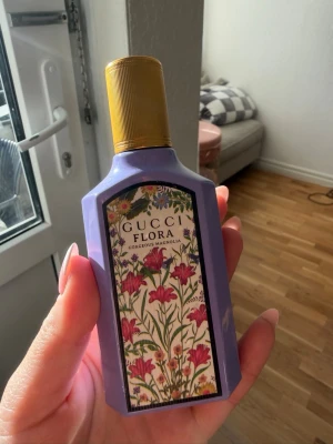 Gucci Flora Gorgeous Magnolia parfym - Gucci Flora Gorgeous Magnolia Eau de Parfum i en lila flaska med guldfärgad kork och blommigt motiv på etiketten. Flaskan har en elegant, kantig form och rymmer 50 ml. Perfekt för dig som gillar lyxiga och feminina dofter. Provad några gånger