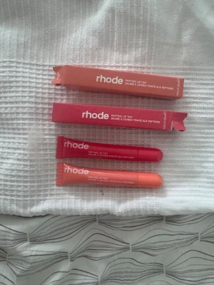 Rhode Peptide Lip Tint duo - Säljer två Rhode Peptide Lip Tint läppbalsam i tub, en i varm persikoton och en i djup rosa nyans. Båda kommer i originalförpackning och har en smidig applikator. Perfekt för dig som vill ha återfuktade och lätt färgade läppar. Oanvänt, förpackningarna är endast öppnade för att visa att produkten faktiskt finns!