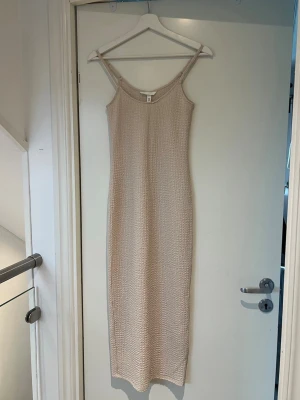 Beige ribbad klänning, XS - Säljer en beige klänning med ribbad struktur och smala axelband. Klänningen har en slits nedtill. Använt den 1 gång💖