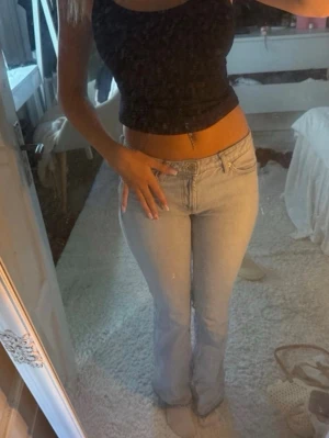 Ljusblå lågmidjade bootcut jeans - Säljer ett par ljusblå bootcut jeans med klassisk femficksdesign och låg midja. Jeansen har en snygg, lätt utsvängd passform och är perfekta till crop tops eller hoodies. Materialet är mjukt denim som ger en skön känsla hela dagen. Jeansen är klippta för att passa någon som är max 170 cm lång. 