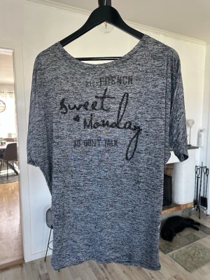 Gråmelerad t-shirt med text - Gråmelerad t-shirt med svart text och paljett-detaljer framtill. T-shirten har korta ärmar och en avslappnad passform. Perfekt för en chill och stilren look.