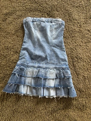 Axelbandslös jeansklänning med volanger - Helt ny och oanvänd jeans kläning ifrån Gina Tricot. 14+ storlek 