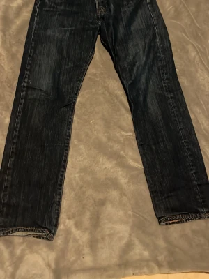 Mörkblå raka jeans - Säljer ett par mörkblå jeans med rak passform och klassisk femficksdesign. Jeansen har diskreta slitningar och kontrastsömmar. Perfekta för en avslappnad stil och tillverkade i denim.