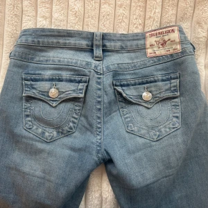 Ljusblå bootcut jeans från True Religion - Säljer ett par ljusblå jeans från True Religion med bootcut passform och låg midja. De sitter jättefint men har lite defekter längst ner, se bilder. Om det är något du undrar hör av dig☺️