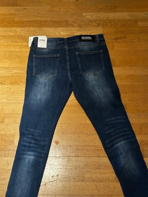 Mörkblå skinny jeans från ICON - Snygga mörkblå skinny jeans från ICON med klassiska fem fickor och slitningar på benen för en trendig look. Jeansen har en smal passform och är tillverkade i stretchigt denimtyg som ger skön komfort hela dagen.