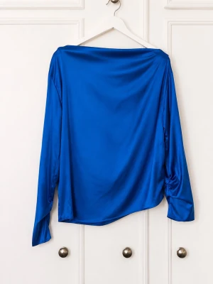 Blå satinsblus med båtringning - Snygg blå satinsblus med båtringning och långa ärmar. Blusen har en lös passform och ett elegant, glansigt material som ger en lyxig känsla. Perfekt att styla med jeans eller kjol för en trendig look.