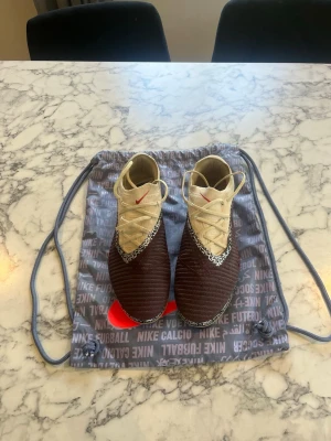 Nike phantom low 6 elite - Helt nya fotbollskor  Bara testade på gräs i 5 minuter med få skott, därför nån jordfläck under sulan Passade verkligen inte mig då den är väldigt små i storleken Köpte 44 men passade verkligen inte så skulle tro att S de passar 42,5-43 Påse får man med men inte orginalboxen då den va skadad av ombudet jag fick den av så den slängdes Lätt prissänkning vid snabb affär