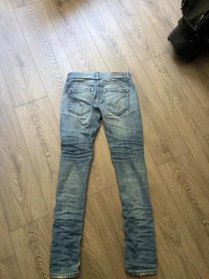 Ljusblå slitna jeans från dondup - Säljer ett par ljusblå jeans dondup  med slitningar  Jeansen har fem fickor, dragkedja och knappgylf samt klassisk dondup detaljen bak  Perfekta för dig som gillar streetstyle.