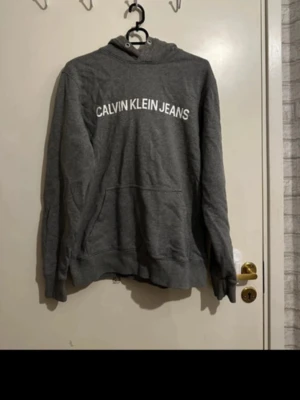 Calvin Klein hoodie - Säljer denna Calvin Klein hoodie. Super fint skick, dock en fläck på ena armen (se bild) men syns inte tydligt alls vid användning. Kom med bud, accepterar de flesta!