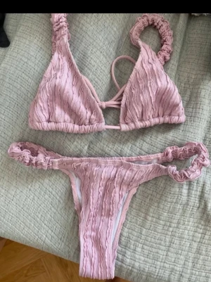 Ljusrosa bikini  - Supersöt ljusrosa bikini med trekantsmodell på toppen och scrunchade axelband samt kanter. 