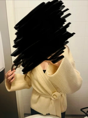 Beige omlottkofta med knytband - Mysig beige omlottkofta i ribbstickat material med breda ärmar och knytband i midjan. Perfekt för lager-på-lager och ger en avslappnad men ändå stilren look. Koftan har en mjuk känsla och passar till många olika outfits.