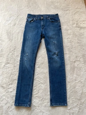 Blå Armani jeans  - Snygga blå jeans från Armani med raka ben och diskreta slitningar framtill. Klassisk femficksmodell med silverfärgade detaljer och logga på bakfickan. Tillverkade i mjuk denim som ger en avslappnad look.