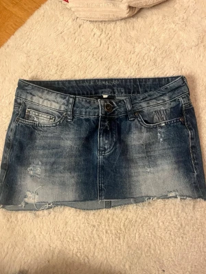 jeanskjol med slitningar - Snygg lågmidjad jeanskjol med slitningar! Midjemått 38cm