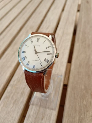 1977 Timex Marlin 31mm Herrklocka - Säljer en unik vintageklocka från brittiska Timex i gott använt skick enligt bilder. Otestad, slitet armband i äkta läder, datumvisare, extra tjockt glas, mekaniskt urverk, baksida i rostfritt stål, vattentät, osv. Ref: 26150 02477.  Begagnat värde: 1000 SEK Mitt pris: 589 SEK  Skriv vid frågor och se gärna mina andra annonser! Skapar gärna deals och paketpriser för just dina behov!   Skickas snabbt och spårbart med alla möjliga fraktsätt.