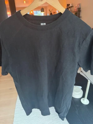 Svart t-shirt från Uniqlo U - En stilren svart t-shirt från Uniqlo U i storlek M. T-shirten har klassisk rund halsringning och korta ärmar. Tillverkad i mjuk bomull som känns skön mot huden. Perfekt basplagg för alla tillfällen.