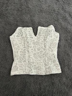 Vit, grå glittrig topp  - Säljer en vit, grå glittrig bandå topp från SHEIN. Som aldrig är använd (endast provad när jag fick hem den) pågrund av för liten. Kvaliten är inte den bästa. Köpte toppen för 70kr. 