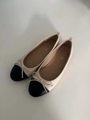 Beige och svarta ballerinaskor med rosett - Beige svarta ballerinaskor. Storlek 37. Från Eurosko. Använda några gånger