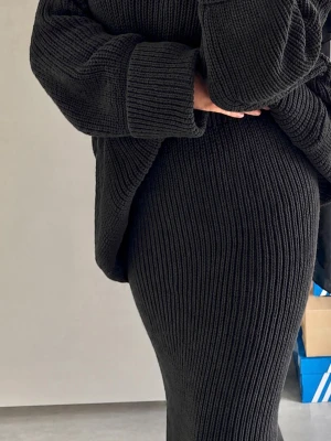 Svart ribbstickad tröja och kjol - Säljer ett set med svart ribbstickad tröja och matchande maxi kjol. Tröjan har oversized passform med breda ärmar och kjolen är figurnära och lång. Perfekt för dig som gillar en stilren och mysig look i mjukt stickat material.