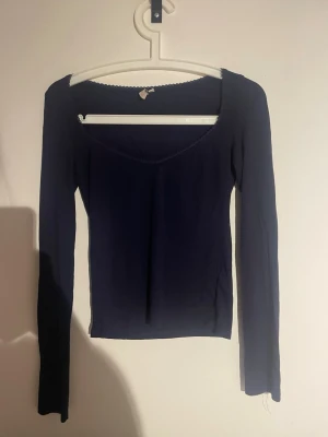 Mörkblå långärmad topp från Nelly - Mörkblå långärmad topp från Nelly med v-ringning och diskret spetskant vid halsen. Toppens passform är slim och materialet känns mjukt och stretchigt, perfekt för en stilren look.