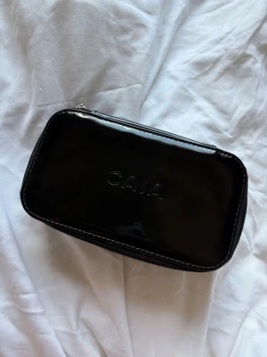 Svart caia necessär - Säljer Caia necessär, black small organizer. Den är i i helsvart med fint Caia märke på toppen. Ägt länge men inte kommit till användning på senaste, därav små defekter (små på insidan, syns på sista bilden) samt vissa repor på utsidan som endast syns i vissa ljus, syns inte i helhetsintryck. Perfekt storlek att ha i väskan💗 Använd gärna KÖP NU💓