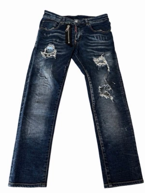 Blå distressed jeans med dragkedja inte fast pris ! - Säljer ett par blå jeans med slitningar och distressed detaljer. Jeansen har en unik stor dragkedja framtill och klassisk femficksmodell. Tillverkade i Italien och har en cool, avslappnad vibe. Perfekta för dig som gillar streetstyle.