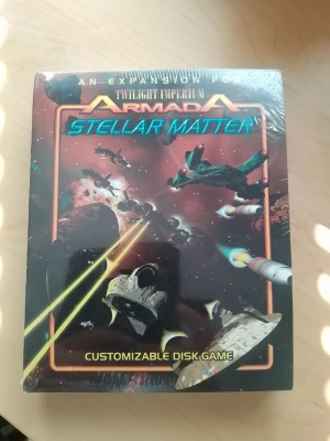 Twilight Imperium Armada Stellar Matter - Expansionen Stellar Matter till Twilight Imperium Armada är ett customizable disk game med rymdtema. Omslaget är svart med färgstarka illustrationer av rymdskepp, explosioner och laserstrålar. Boxen är rektangulär och tillverkad i kartong.