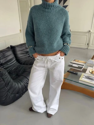 Vita vida jeans med snörning - Intressekoll på ett par vita jeans med låg midja och vida ben. Lite smutsiga längst ned men inget som märks. Jeansen har snörning i midjan och silverfärgade nitar längs linningen för en cool detalj. Perfekta för dig som gillar en avslappnad och trendig stil. Priset kan diskuteras
