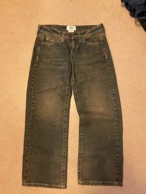 Baggy jeans med raka ben - Säljer ett par mörkblå baggy jeans med raka ben och slitna detaljer. Jeansen har klassiska fem fickor och kontrastsömmar. Perfekta för en avslappnad streetwear-look. Materialet är kraftig denim.