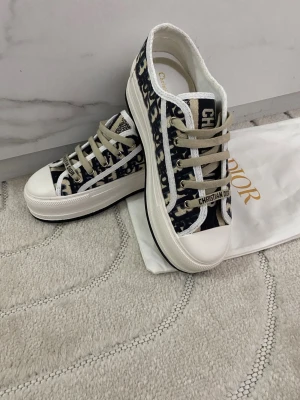 Platform sneakers med monogrammönster 37 - . Skorna har vita sulor, beige snörning och tydlig logga på plösen. Tillverkade i canvas med detaljer i gummi. Perfekta för dig som vill ha en trendig och exklusiv look.