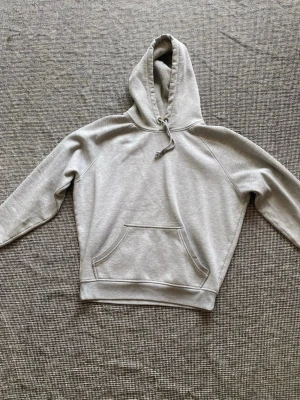 Ljusgrå hoodie med magficka - Säljer en stilren ljusgrå hoodie med huva och dragsko. Hoodien har en klassisk magficka och ribbade muddar vid ärmslut och nederkant. Pruta gärna!🥰 